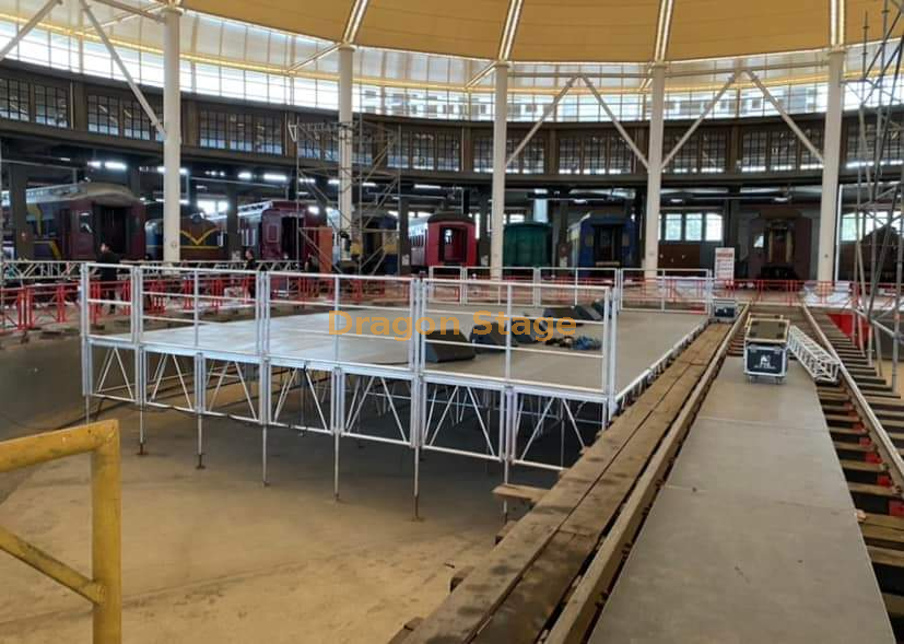  铝制栏杆舞台平台 12x8m，设有 2 个通道楼梯和沿舞台后部的装卸坡道